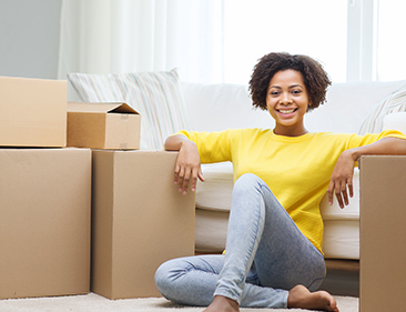 woman in yellow sweater sitting on the floor amidst moving boxes