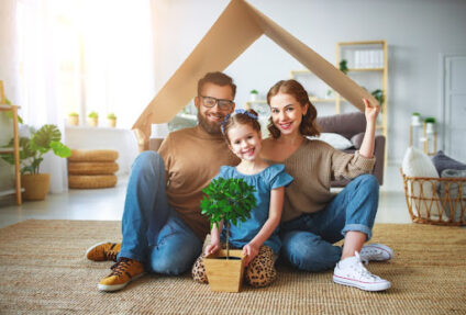 Family smiling under a cardboard roof.