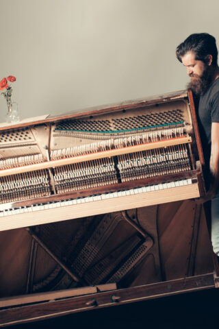 Man struggling to move a fragile piano by himself