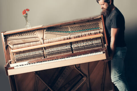 Man struggling to move a fragile piano by himself