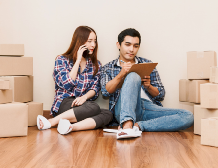 Young couple checking off checklist with cardboard moving boxes around them