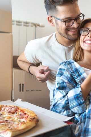 A couple eating pizza and smiling.