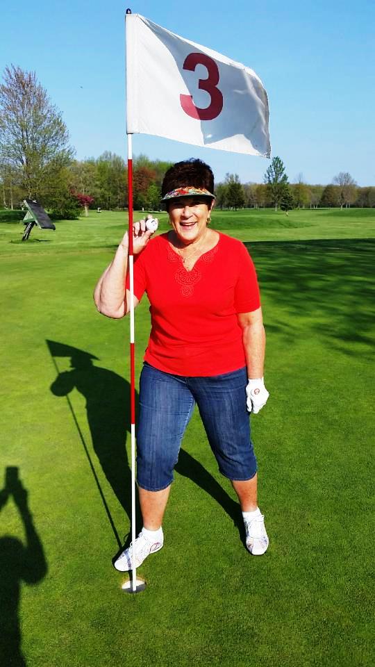 woman in red tshirt posing on a golf course