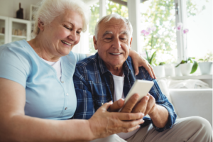 Older couple smiling looking at phone.