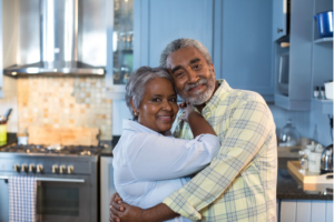 Senior couple hugging and smiling looking at camera. 