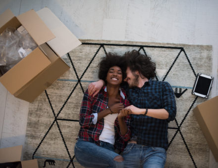 couple laying on rug in new home amidst moving boxes