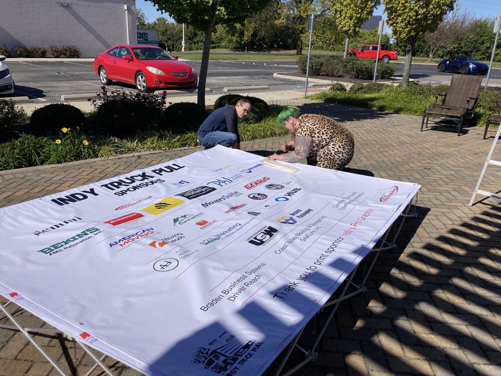 Wheaton staff sets up sponsor signage at Indy Truck Pull