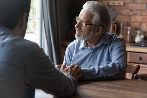 A young man trying to comfort an older man.