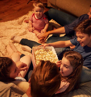 Family sitting on the sofa eating popcorn.