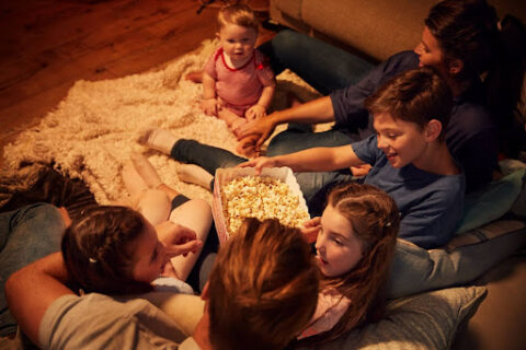 Family sitting on the sofa eating popcorn.